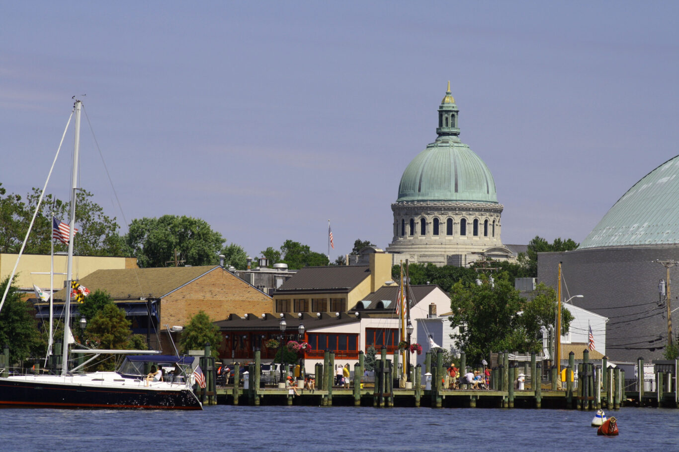 Annapolis, Maryland, USA- August 12, 2012: View of the United States Naval Academy Chapel from a boat in the Annapolis Harbor.  The people strolling on the City Dock are tourists, residents, and business people.  Annapolis is a vibrant colonial city on the Chesapeake Bay.
