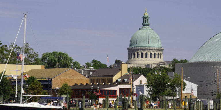 Annapolis, Maryland, USA- August 12, 2012: View of the United States Naval Academy Chapel from a boat in the Annapolis Harbor.  The people strolling on the City Dock are tourists, residents, and business people.  Annapolis is a vibrant colonial city on the Chesapeake Bay.
